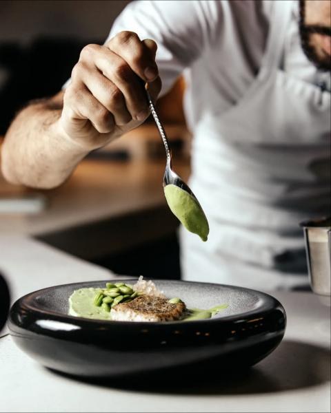Chef Luigi spooning a vibrant green sauce onto a plated dish